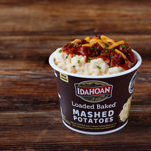 Idahoan Loaded Baked Mashed Potatoes Cup made with chili on a table